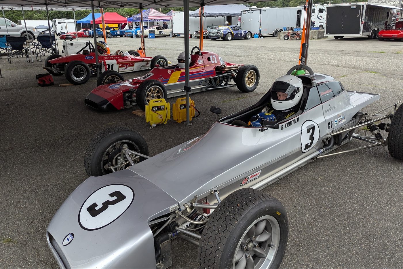 Bill Krutilla strapped into the number 3 car in the paddock, other Formula Fords lined up beside him