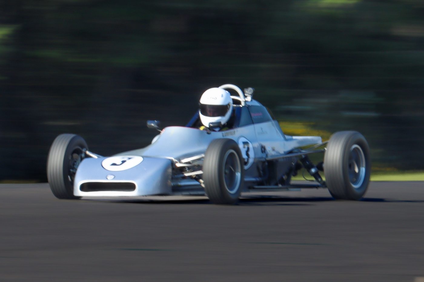 The number 3 Crosslé at speed, front three-quarter view with blurred trees